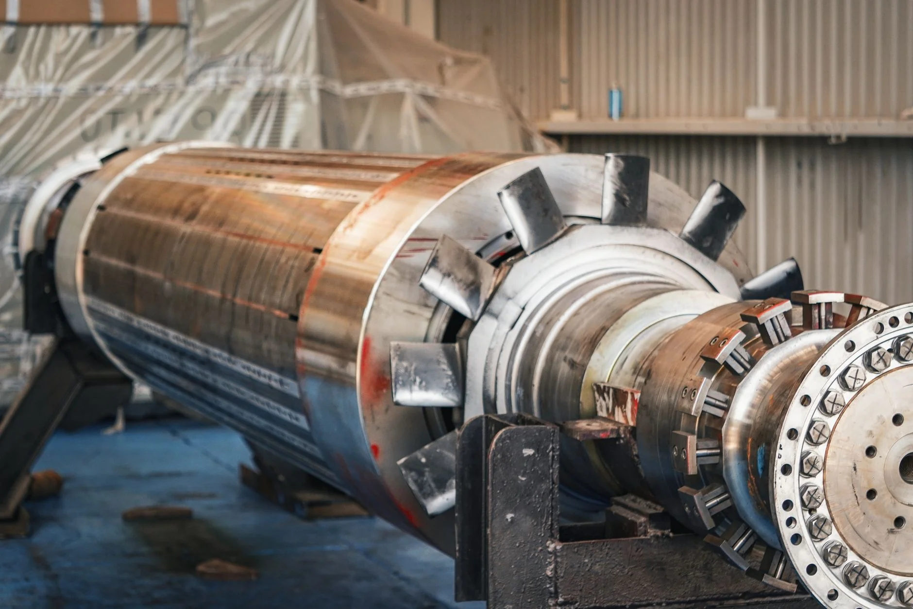 A large machined rotor assembly resting on stands in a fabrication shop, bolted flange and blade root slots exposed, the kind of engineered scope a technical offer has to price