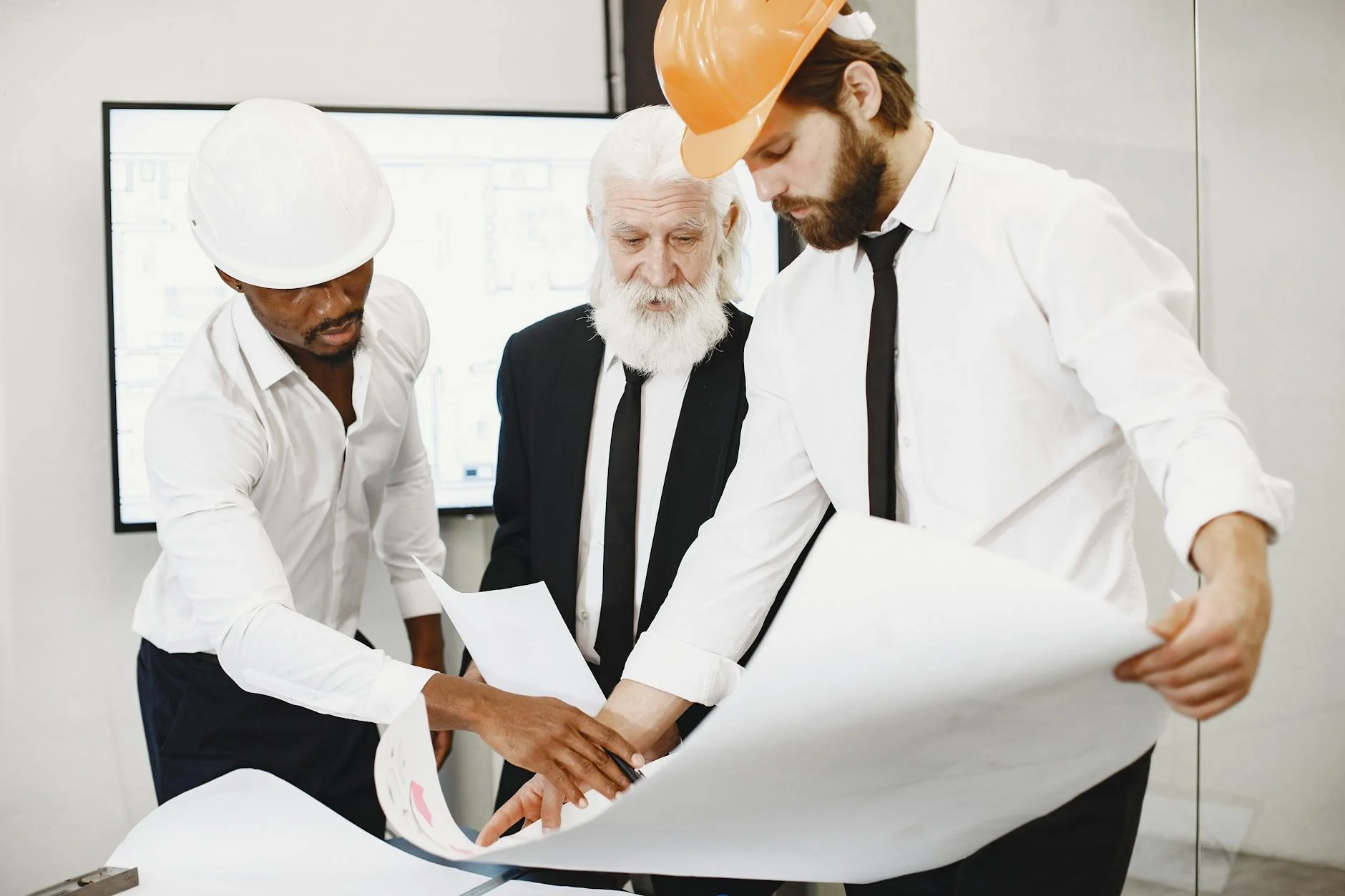 Three engineers reviewing technical plans together in an office