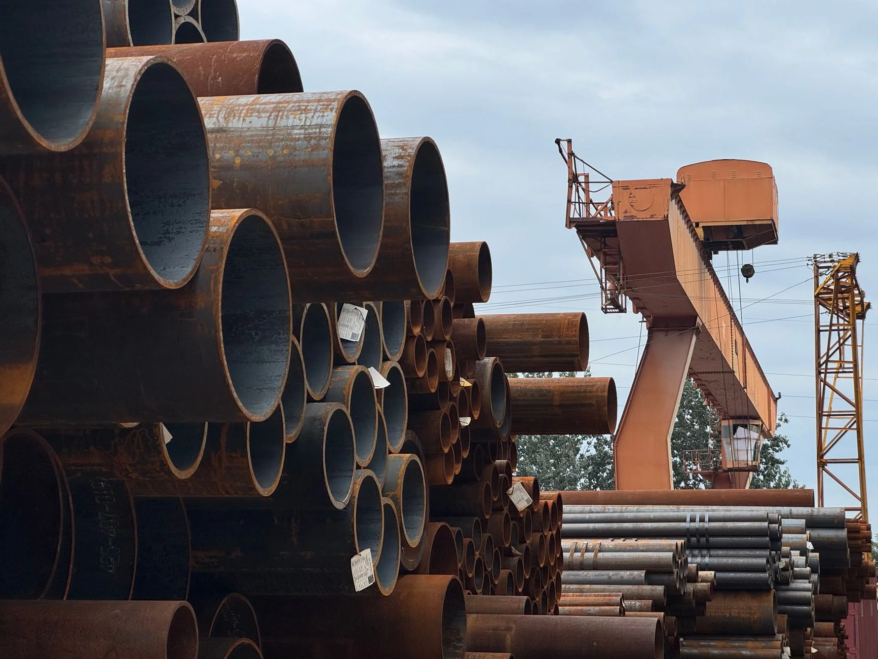 Stacks of large-diameter steel pipe at an industrial manufacturing yard, representing the engineered goods behind a supplier bid package