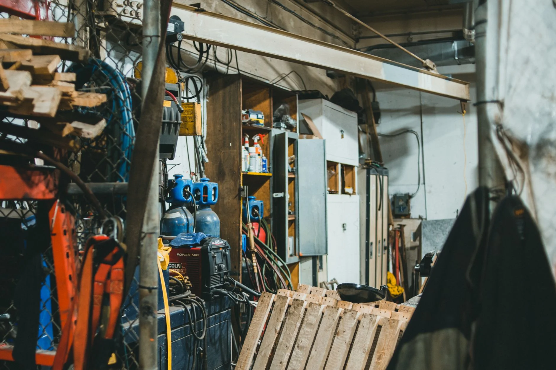 A working shop back-corner of gas bottles, cable reels, timber and tooling, the real conditions behind a clean spec sheet