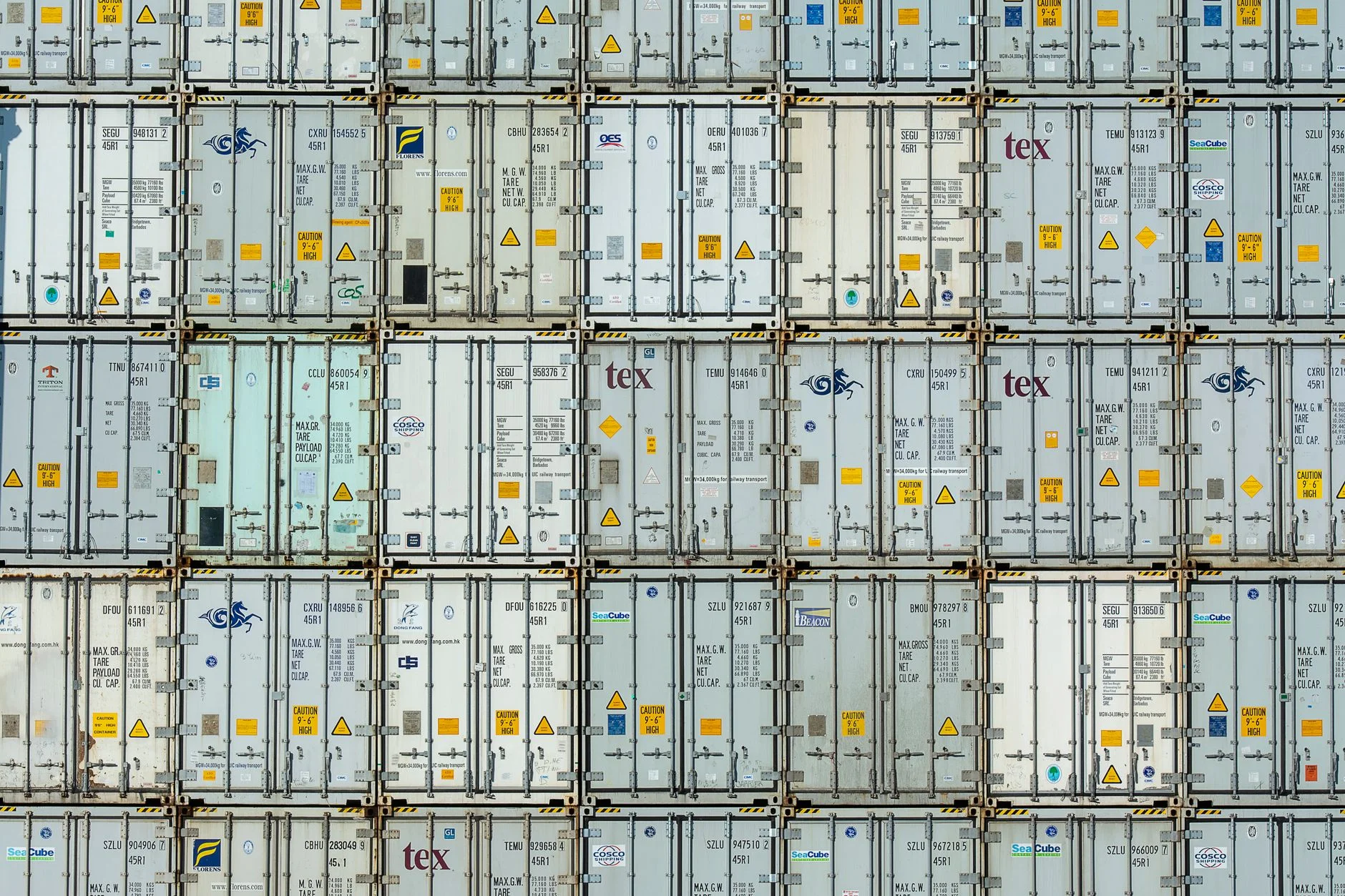 A wall of stacked refrigerated shipping containers, every one carrying its own owner code and serial