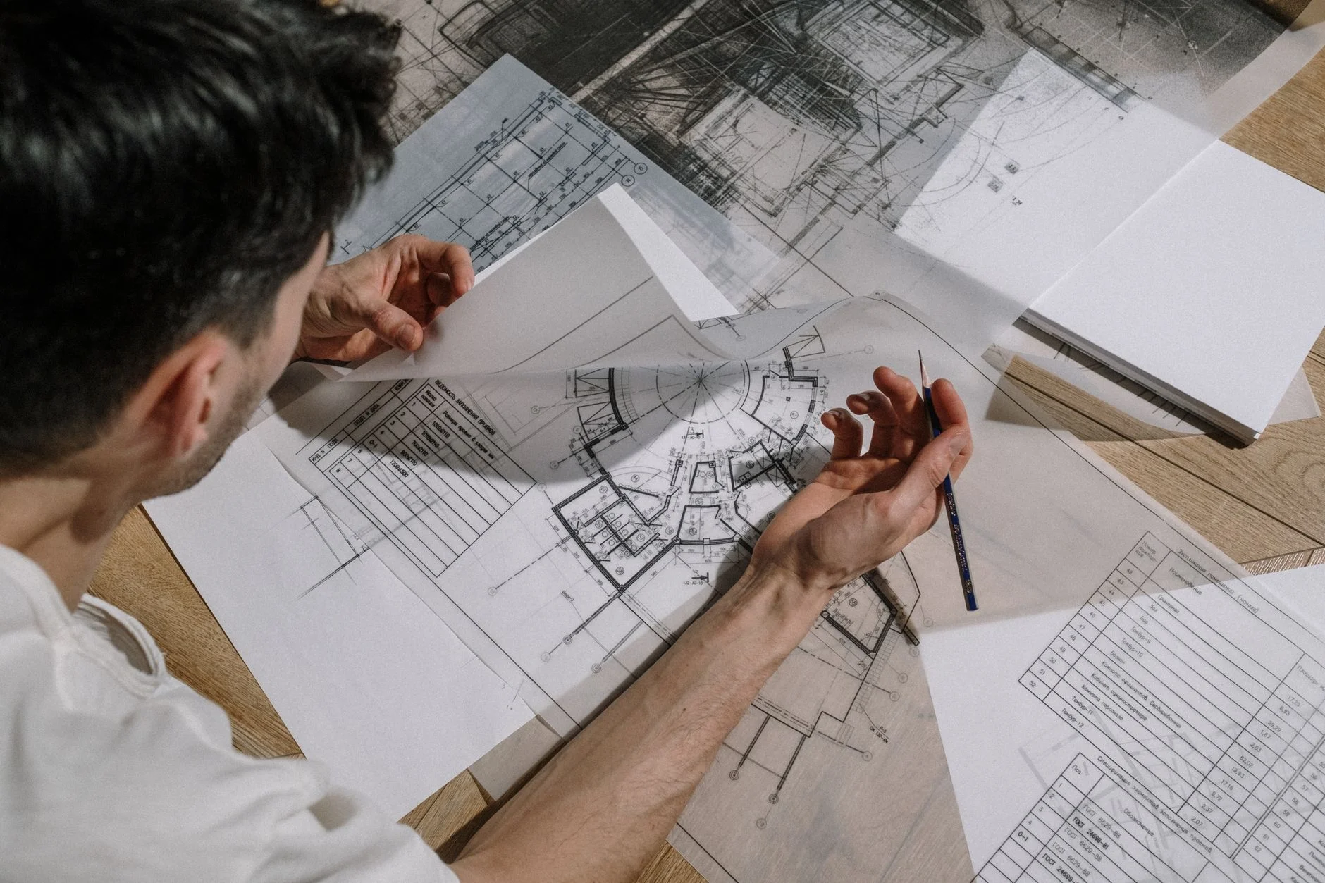 Engineer studying and marking up detailed technical drawings with a spec table visible