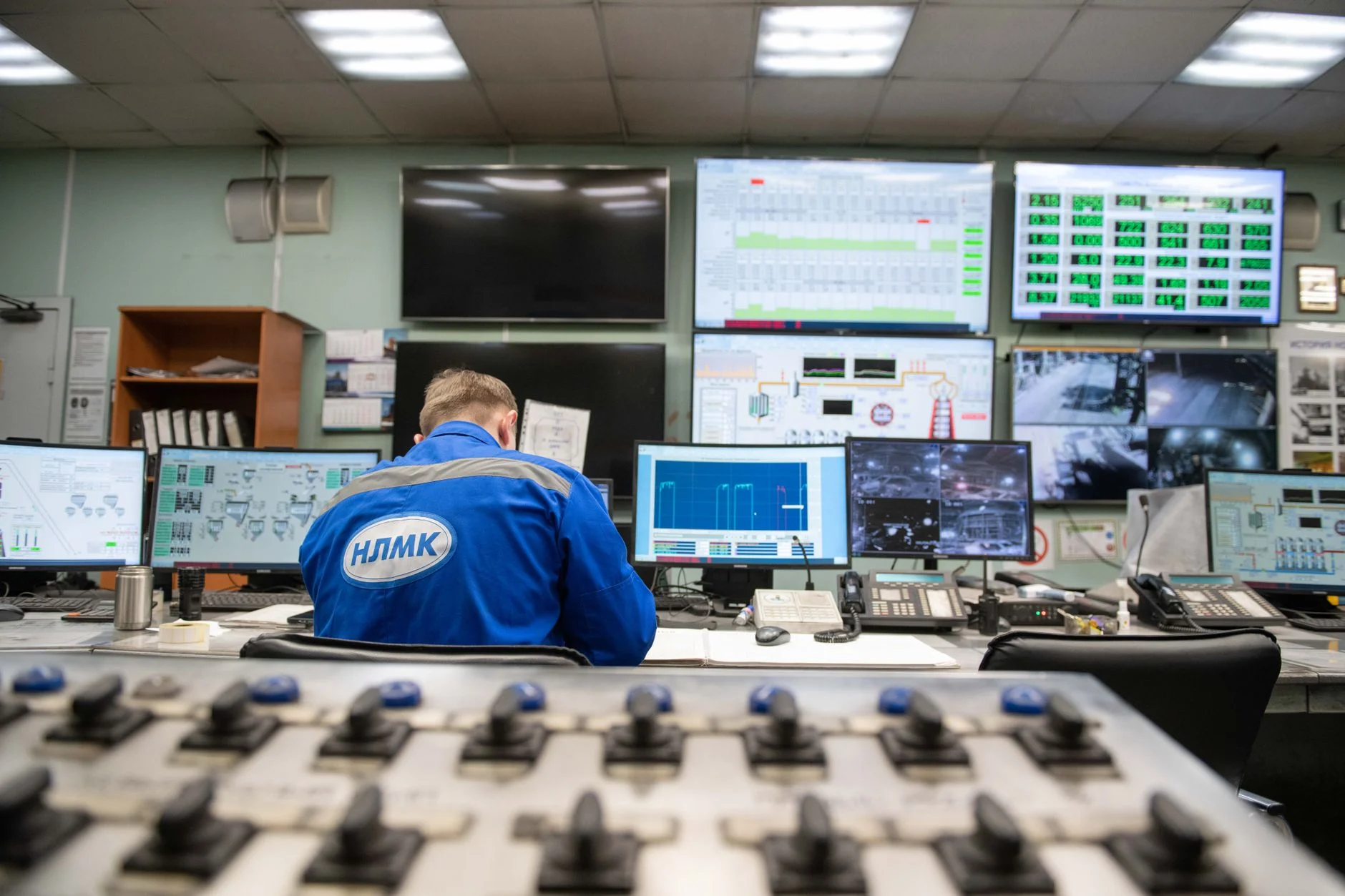 An engineer monitors multiple screens in an industrial control room