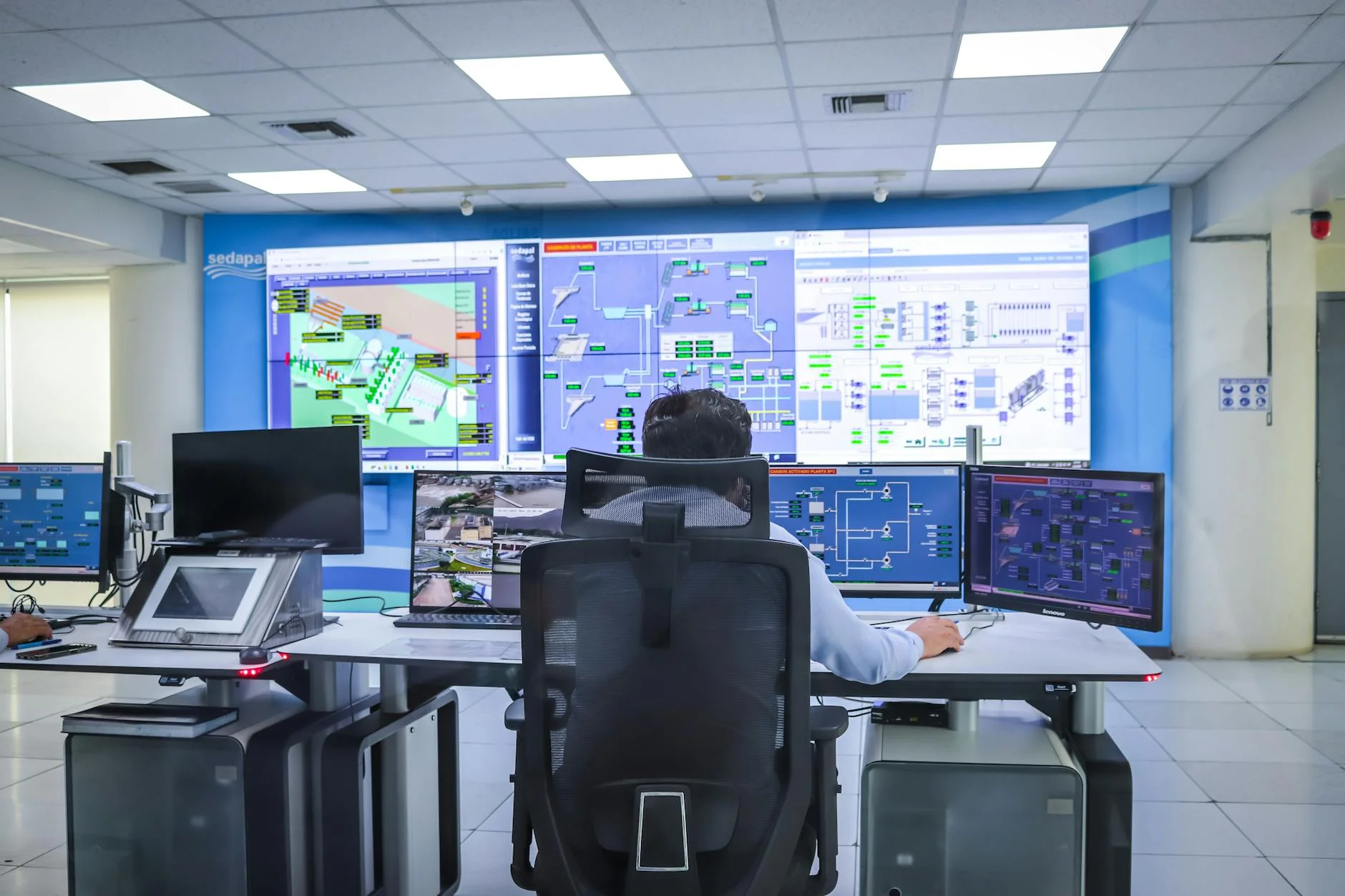 Operator in an industrial control room monitoring multiple systems