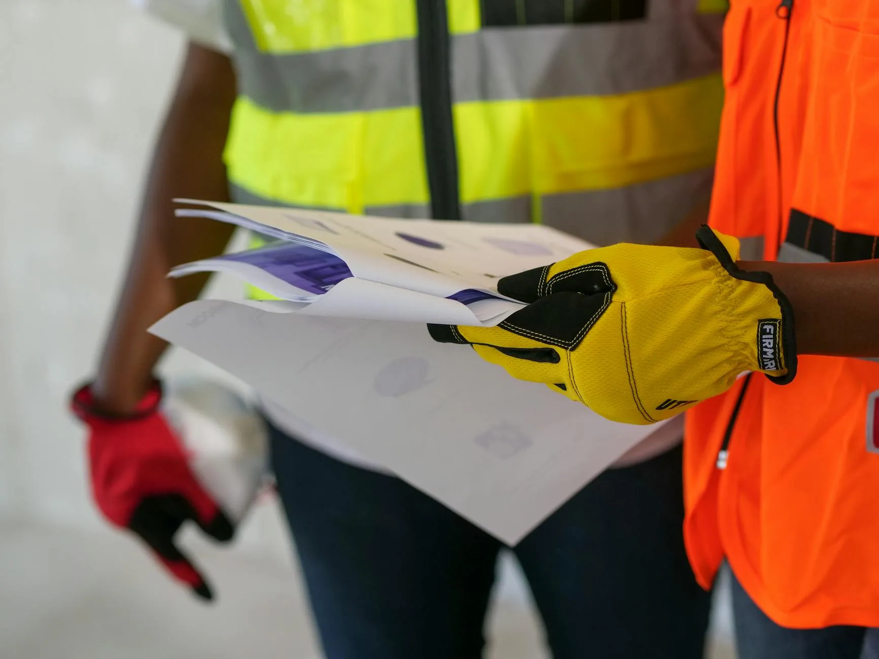 Industrial workers in PPE reviewing proposal documents on-site — the inquiry-to-order workflow that happens before any order is placed.